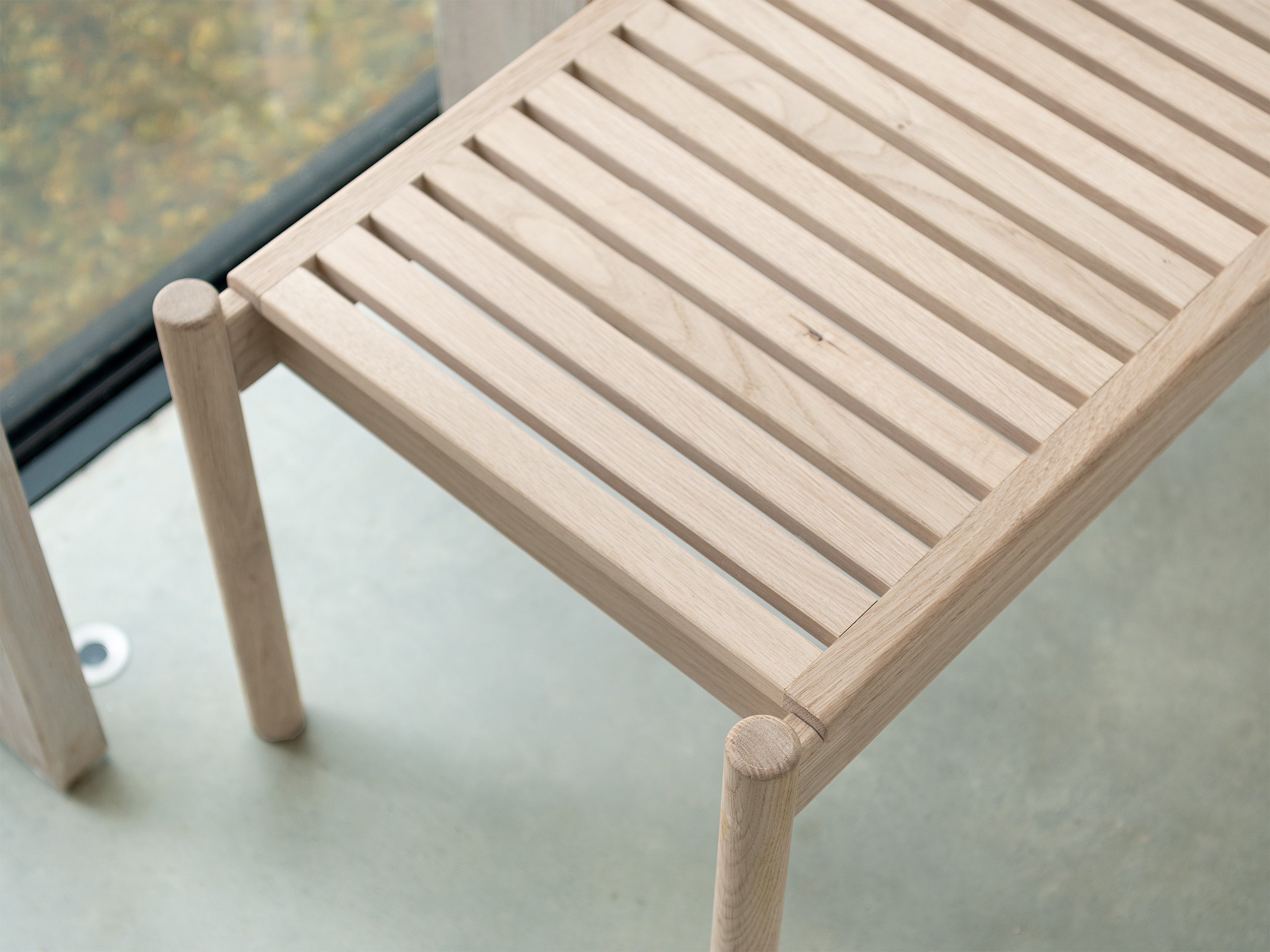 Looking down on the detail of the slatted indoor bench of light oak
